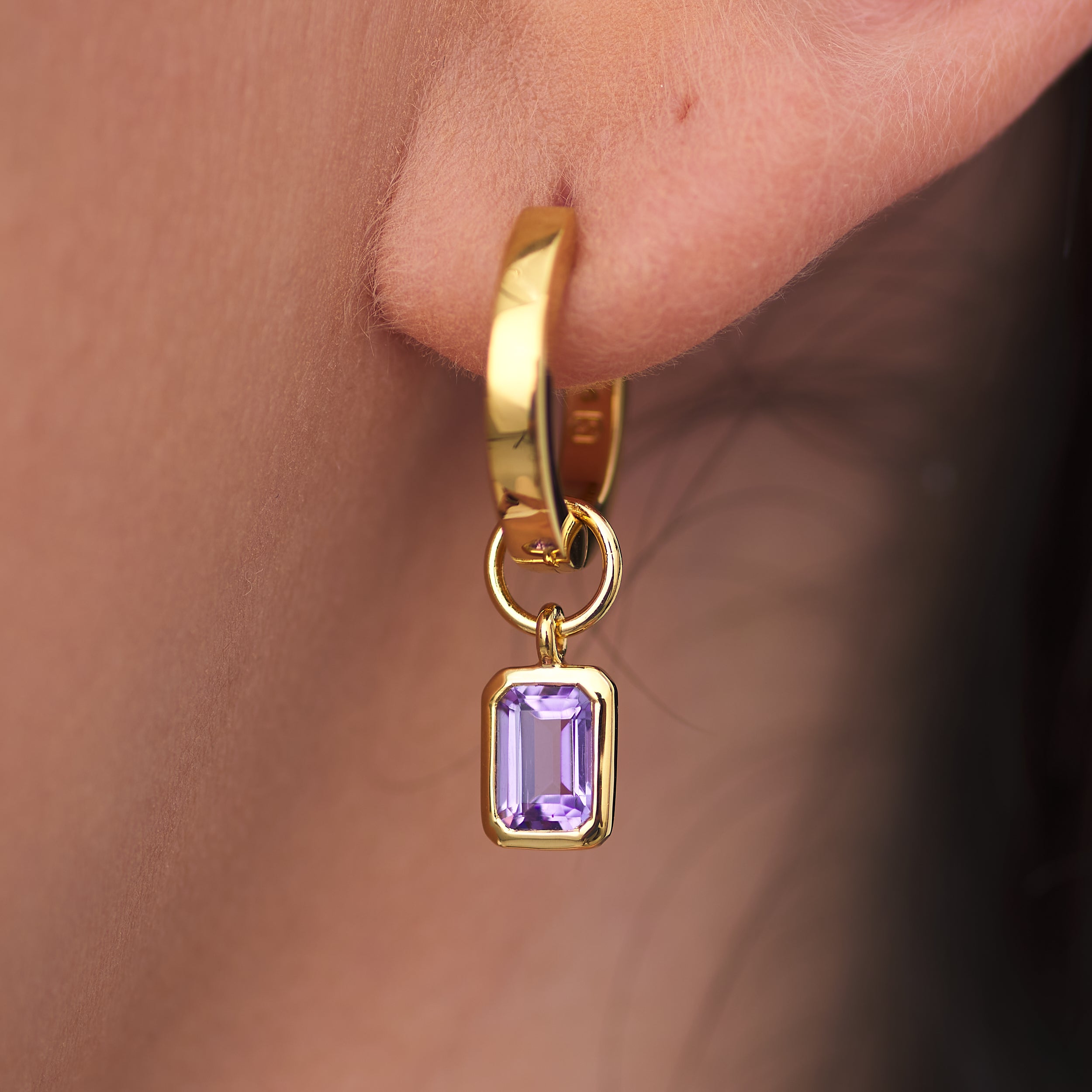 Close-up of 18K gold vermeil amethyst huggie hoop earrings with interchangeable charms and amethyst, February's birthstone. Crafted from durable 18K gold vermeil, ideal for those who appreciate luxury and customisable jewellery.