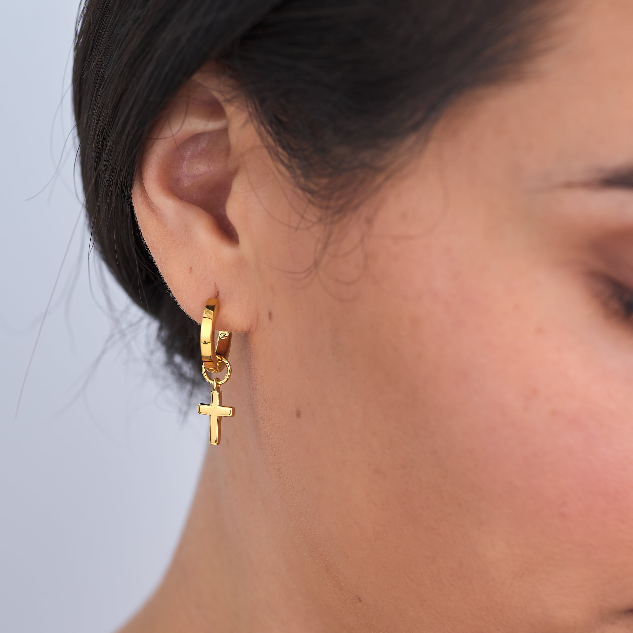 Dainty 18k gold vermeil cross charms attached to everyday gold vermeil huggie hoop earrings. the perfect symbol for devotion.