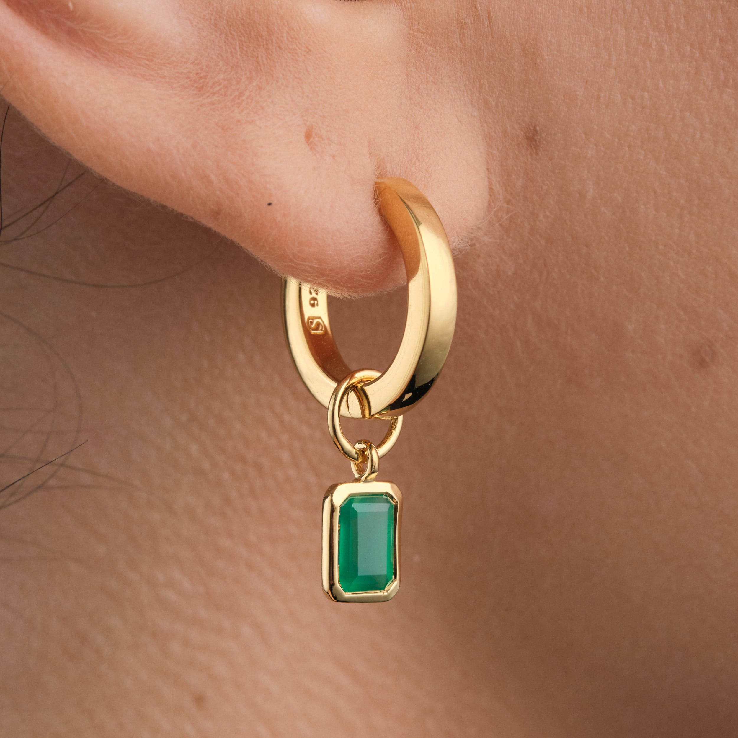 Close-up of 18K gold vermeil huggie hoop earrings with interchangeable green onyx gemstone charms a meaningful and stylish jewellery choice showcasing May’s birthstone, crafted from high-quality gold vermeil for lasting beauty.