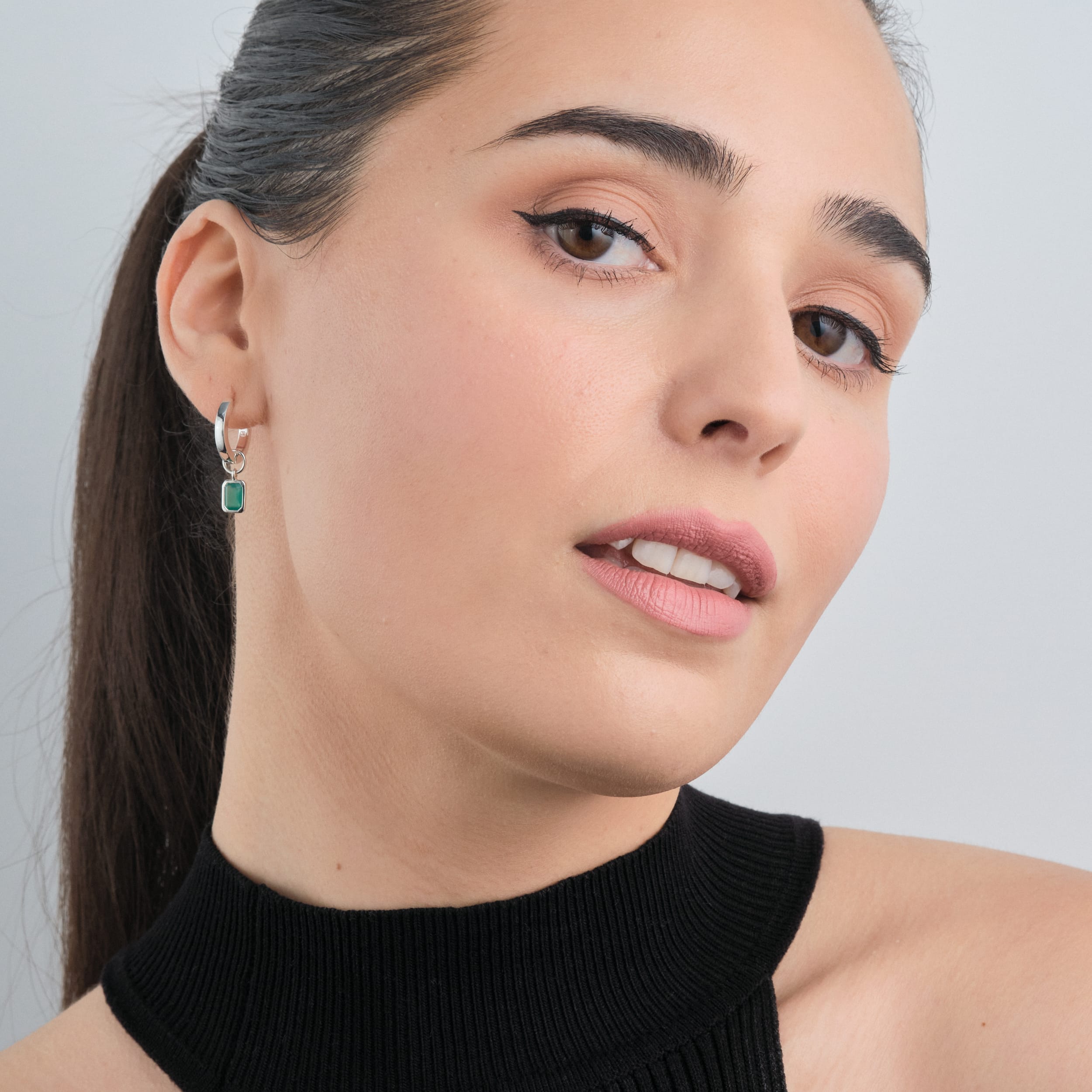 A woman wearing Sterling silver huggie hoop earrings with interchangeable green onyx gemstone charms. The perfect addition to a personalised jewellery collection, featuring May’s birthstone set in hypoallergenic, durable sterling silver for long-lasting elegance.
