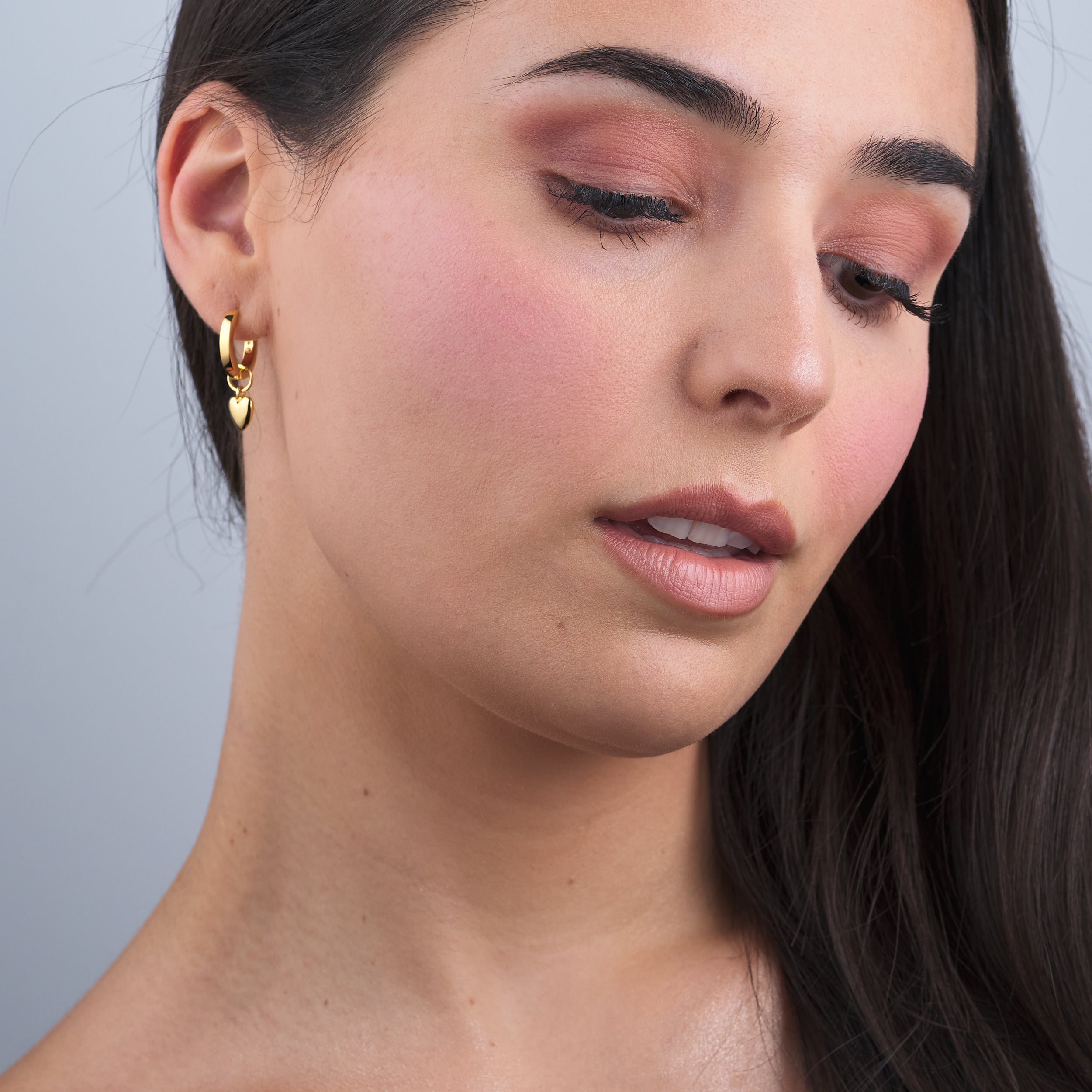 Elegant woman showcasing 18K gold vermeil puffy heart charm huggie hoop earrings, designed with interchangeable charms for a personalised touch, perfect for gifting or everyday wear.