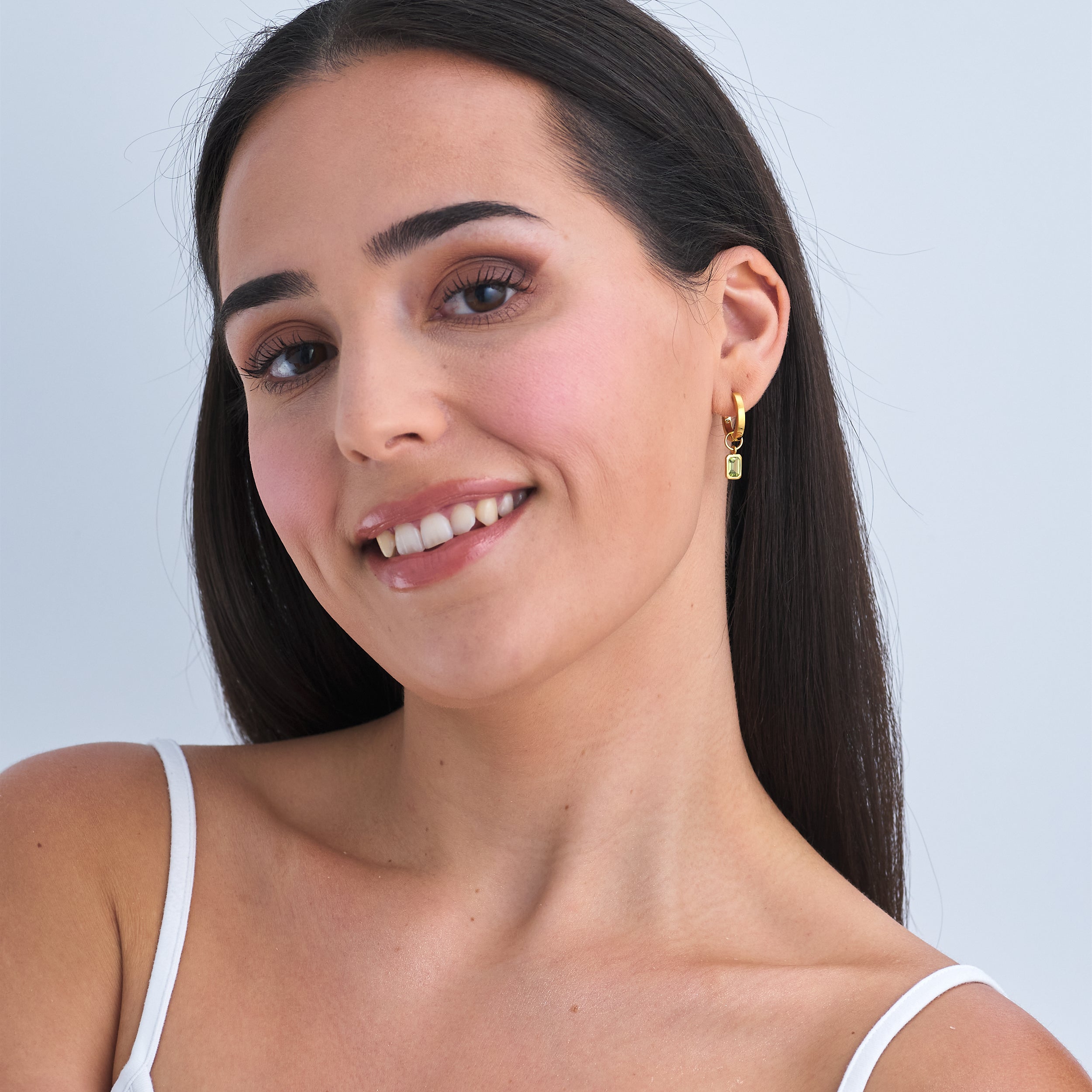 Woman wearing 18k Gold Vermeil huggie hoop earrings with interchange Peridot gemstone charms that are a classic staple to anyone's jewellery collection.