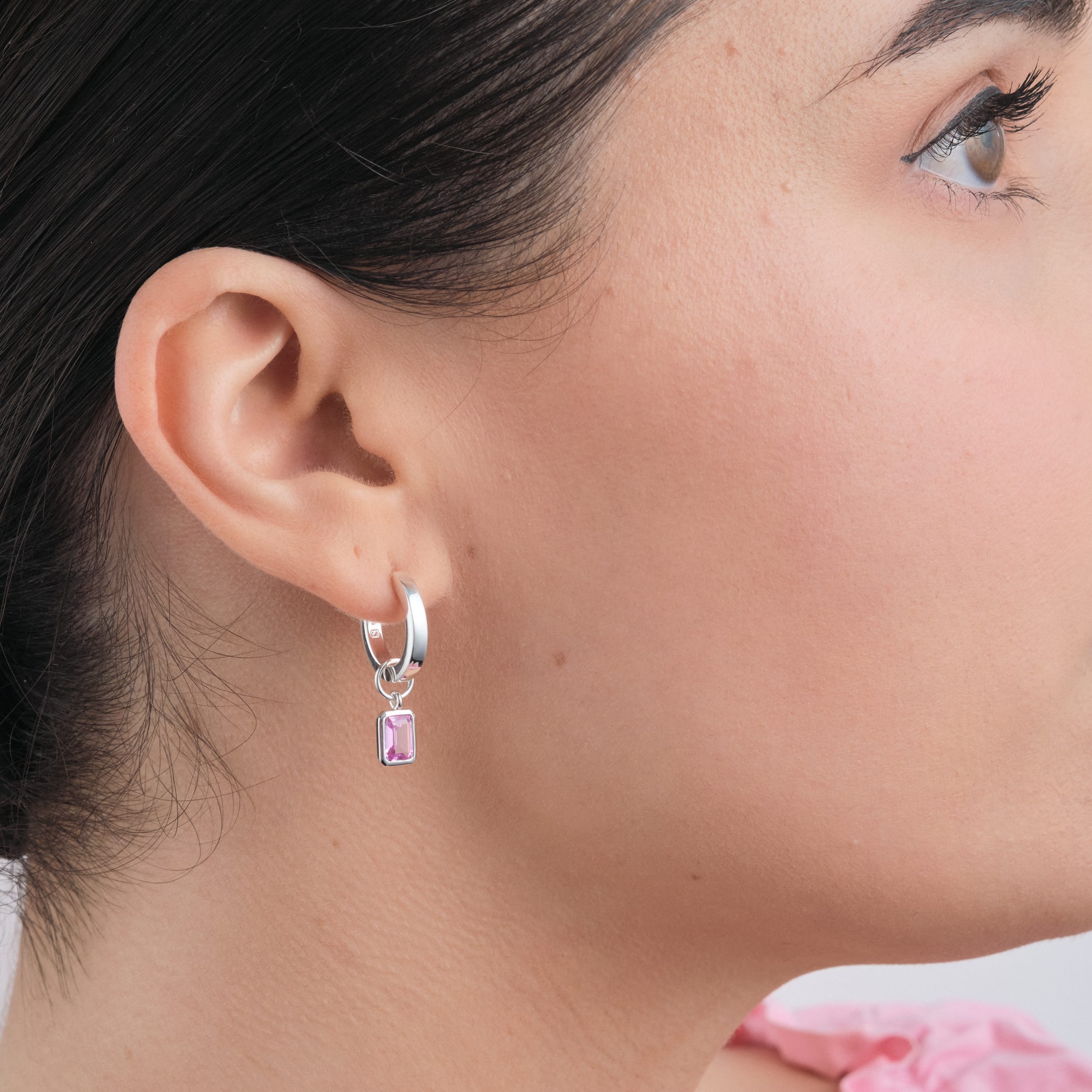 Sterling silver huggie hoop earrings with interchangeable pink ruby gemstone charms. Hypoallergenic and durable, these earrings offer a stylish and affordable luxury option, making them a perfect gift for any occasion.
