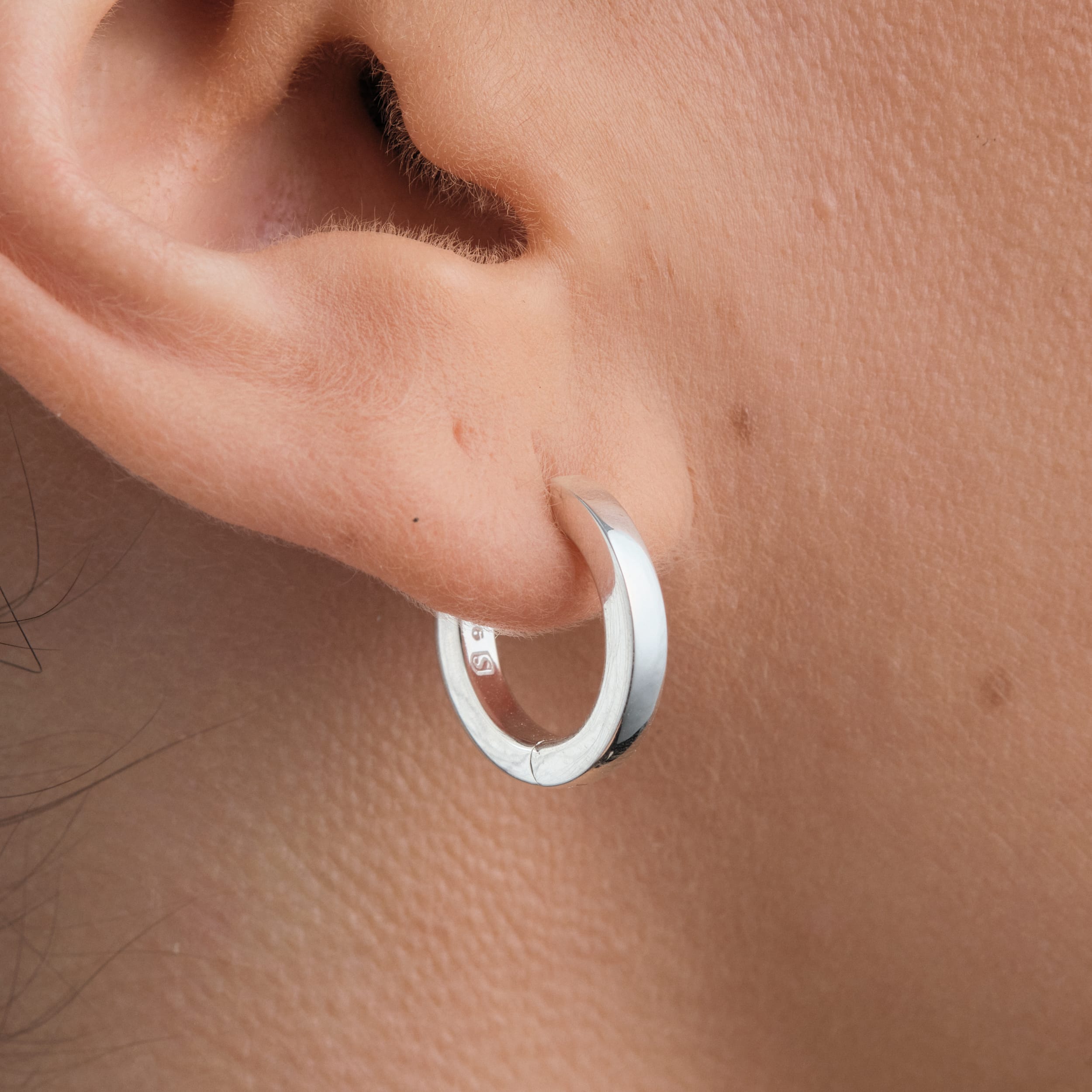 Minimalist 925 sterling silver huggie hoops that are lightweight, tarnish-resistant, and perfect for daily wear without irritation.