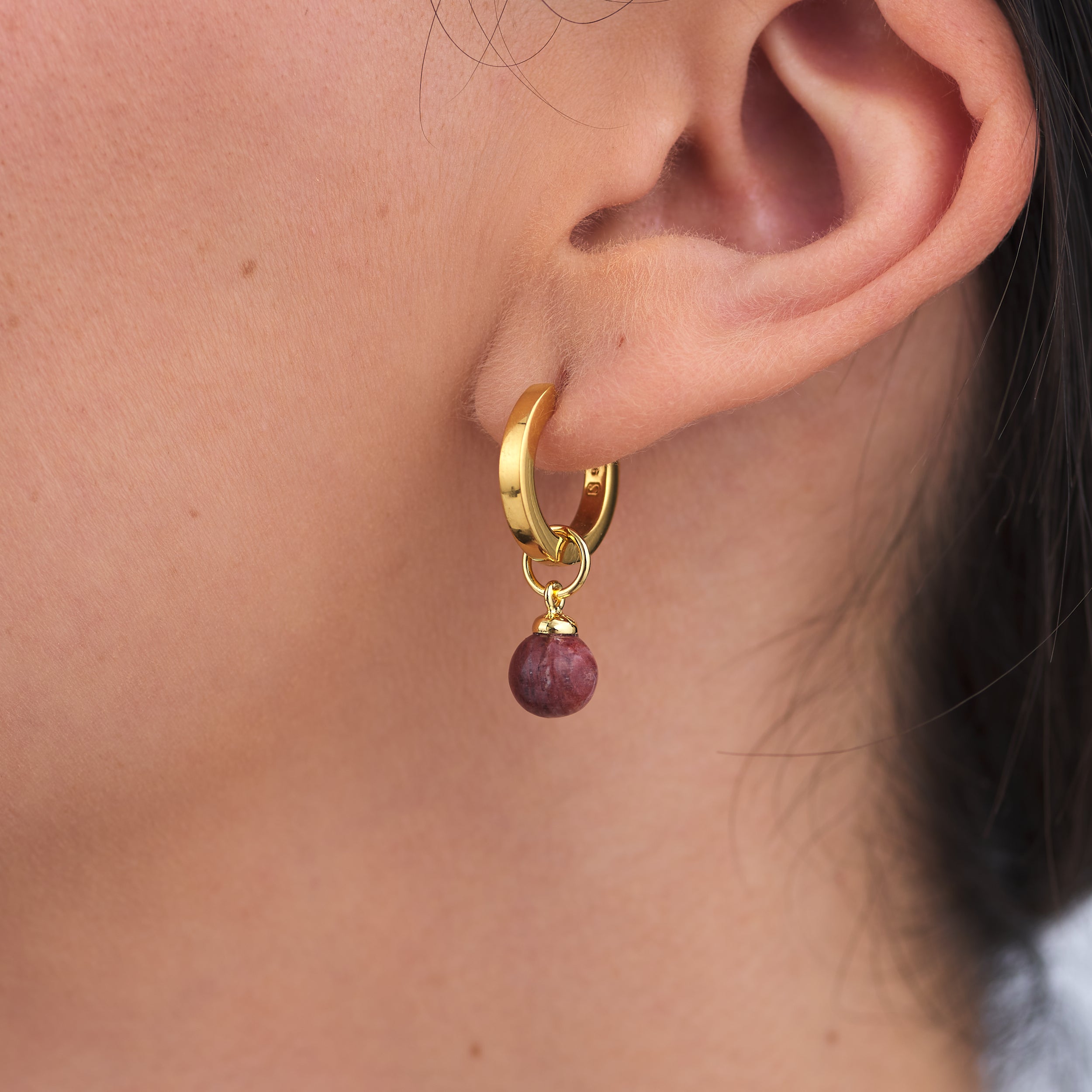 Side veiw of a beautiful woman wearing timeless 18k Gold Vermeil Huggie hoop earring with a interchangeable Sunstone Jasper gemstone charm attached.