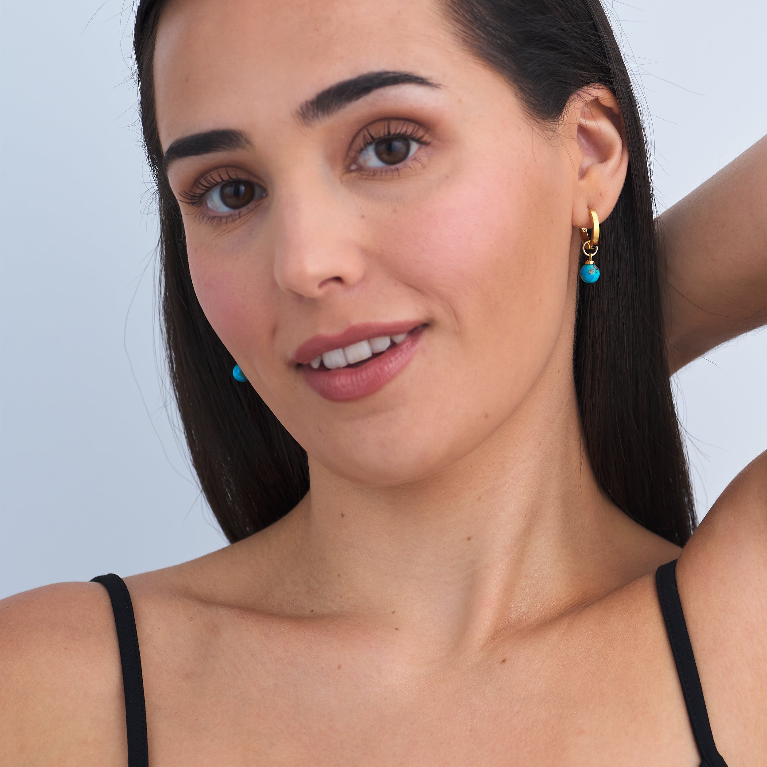 Woman wearing timeless 18k Gold Vermeil Huggie Hoop earrings with personalised Turquoise gemstone charms.