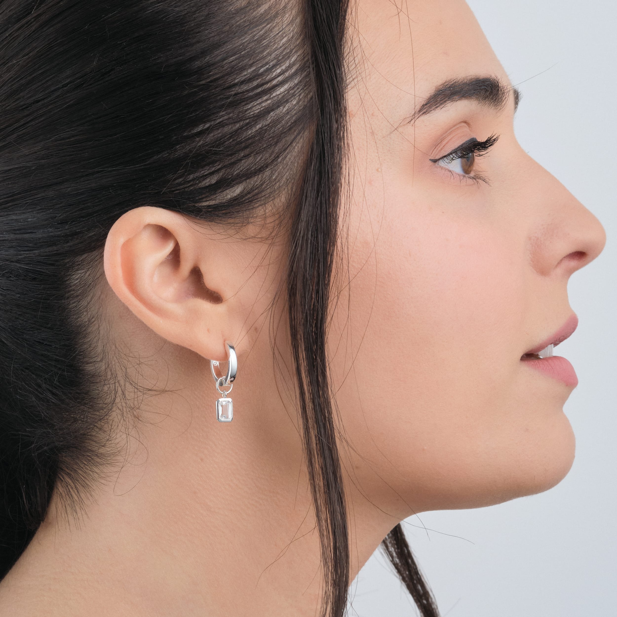 Side view of a woman wearing Sterling silver huggie hoop earrings with detachable white topaz gemstone charms hypoallergenic and crafted for durability, these earrings offer a perfect customisable accessory, ideal for creating a personalised look with the versatility of sterling silver.